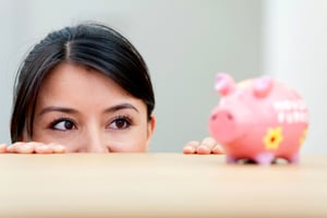 Beautiful woman looking at her savings in a piggybank-1