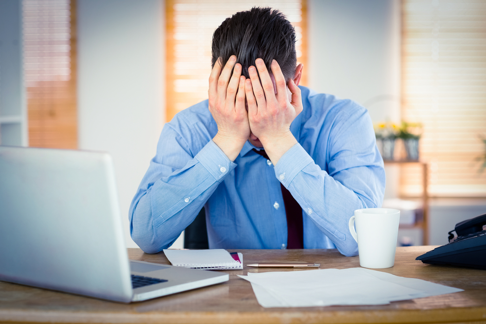 Stressed businessman with head in hands at office